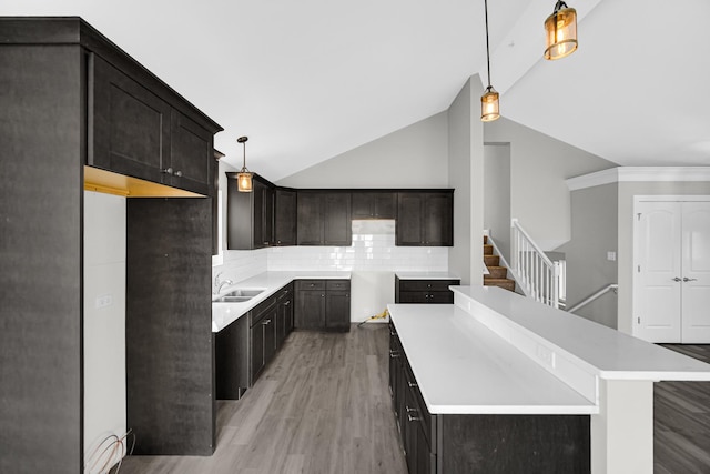 kitchen featuring a center island, decorative light fixtures, light hardwood / wood-style floors, backsplash, and vaulted ceiling