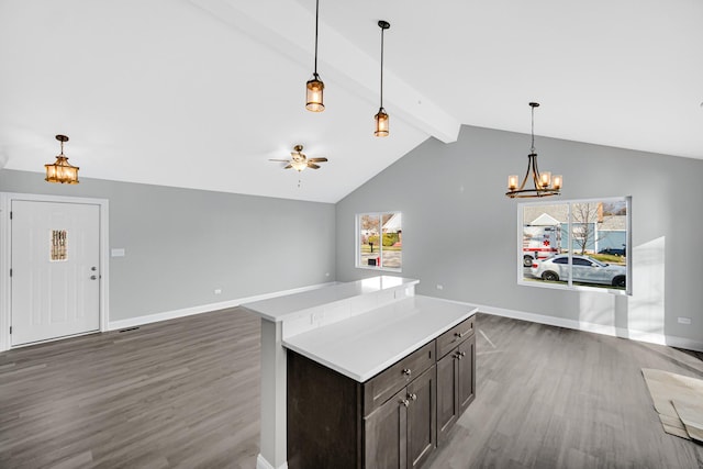 kitchen with beamed ceiling, hanging light fixtures, dark brown cabinets, a kitchen island, and dark hardwood / wood-style floors