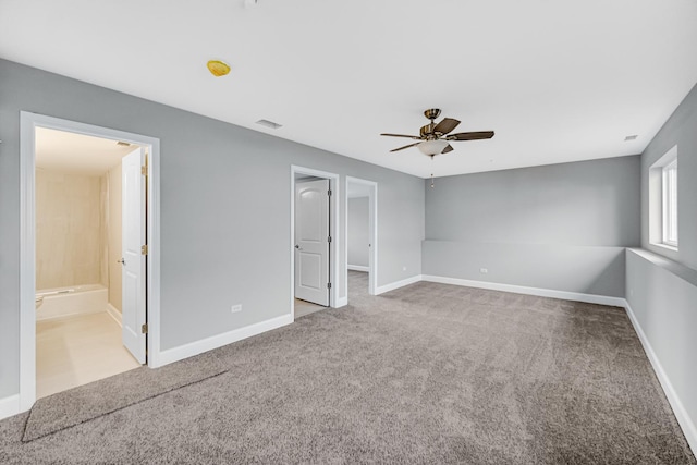 interior space featuring ceiling fan, light carpet, and ensuite bath