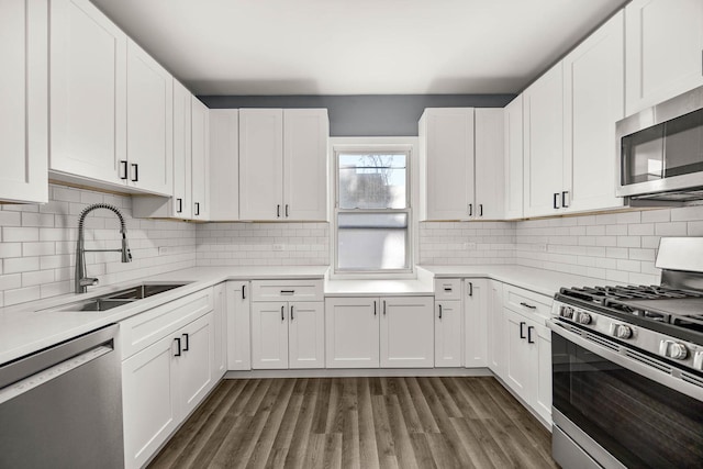 kitchen with appliances with stainless steel finishes, dark hardwood / wood-style flooring, tasteful backsplash, sink, and white cabinetry