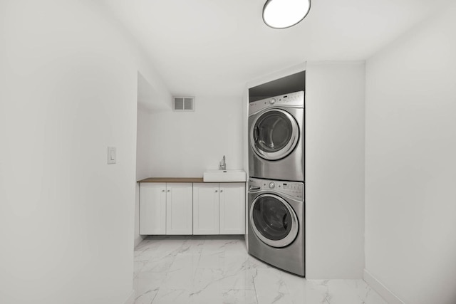 laundry room with stacked washer / drying machine, cabinets, and sink