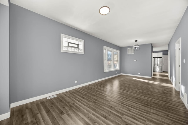 unfurnished living room with dark wood-type flooring and a notable chandelier