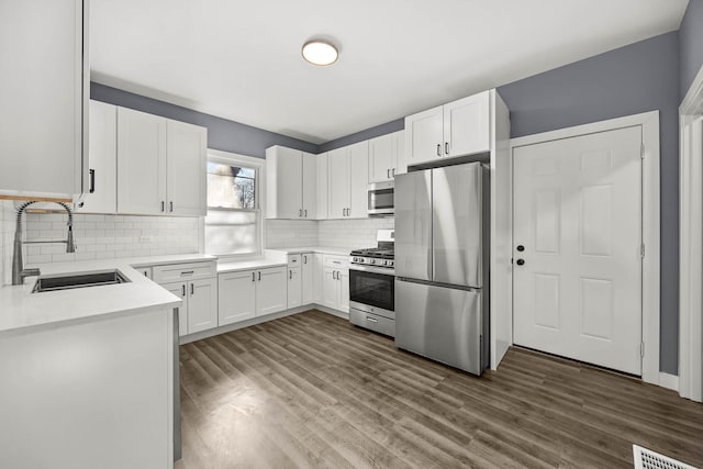 kitchen with decorative backsplash, stainless steel appliances, dark wood-type flooring, sink, and white cabinetry