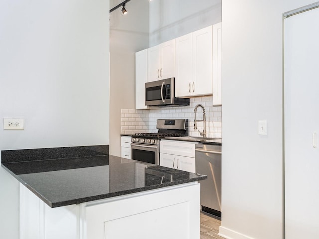 kitchen featuring white cabinetry, sink, light hardwood / wood-style flooring, backsplash, and appliances with stainless steel finishes