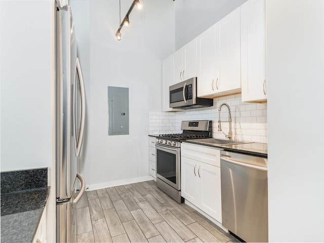 kitchen with sink, stainless steel appliances, light hardwood / wood-style flooring, electric panel, and white cabinets