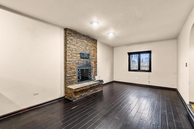 unfurnished living room with hardwood / wood-style floors and a stone fireplace