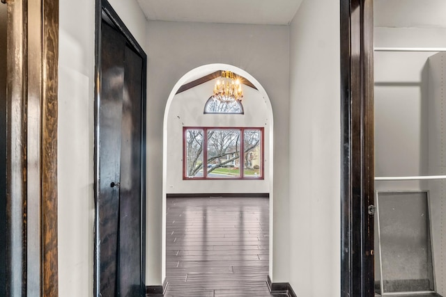 hall featuring wood-type flooring and a notable chandelier