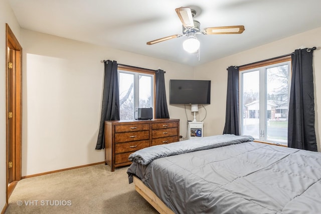 bedroom with multiple windows, ceiling fan, and light carpet