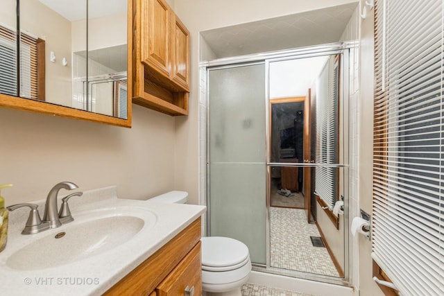 bathroom featuring tile patterned flooring, vanity, toilet, and a shower with shower door