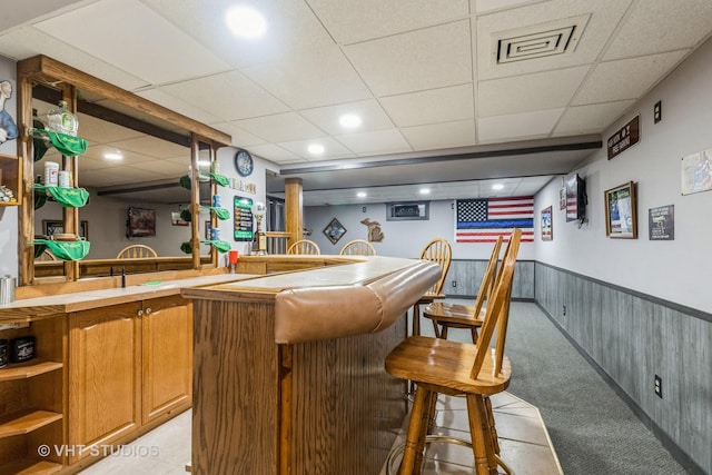 bar featuring a drop ceiling, wood walls, and light colored carpet