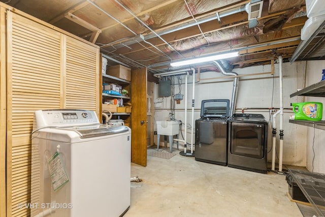 washroom with electric panel, washer and clothes dryer, and sink