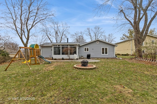 rear view of property featuring a fire pit, a sunroom, a playground, and a yard