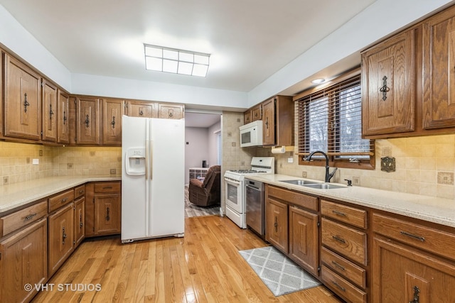 kitchen with tasteful backsplash, sink, stainless steel appliances, and light wood-type flooring