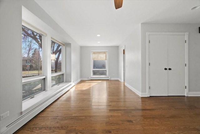 empty room with baseboard heating, dark wood-type flooring, and ceiling fan