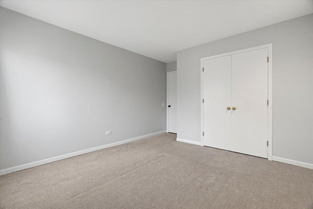 unfurnished bedroom featuring light colored carpet and a closet