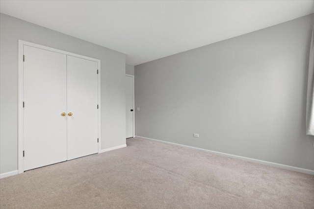 unfurnished bedroom with light colored carpet and a closet