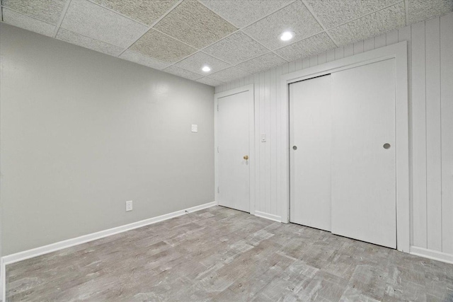 unfurnished bedroom with a paneled ceiling, light hardwood / wood-style flooring, and a closet