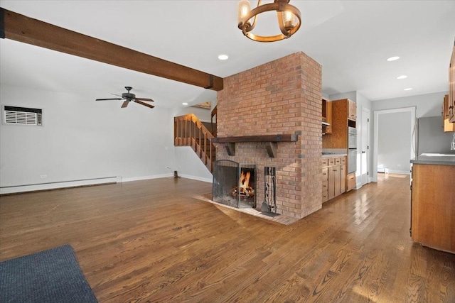 living room with ceiling fan, dark hardwood / wood-style flooring, beamed ceiling, a baseboard heating unit, and a fireplace