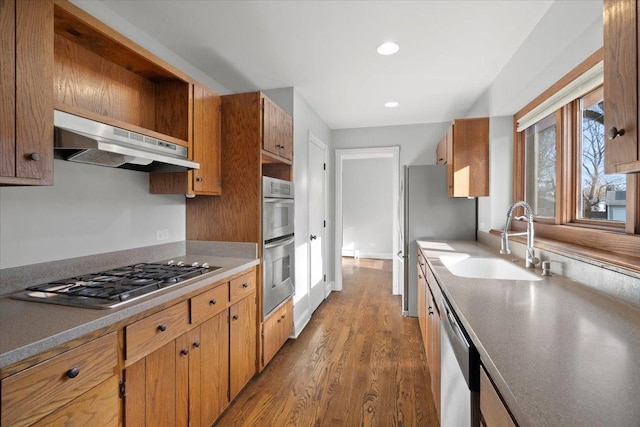 kitchen featuring sink, appliances with stainless steel finishes, dark hardwood / wood-style flooring, and range hood