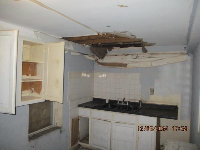 kitchen with tasteful backsplash, sink, and white cabinets