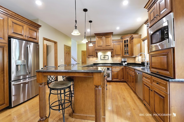 kitchen with stainless steel appliances, sink, decorative light fixtures, dark stone countertops, and backsplash