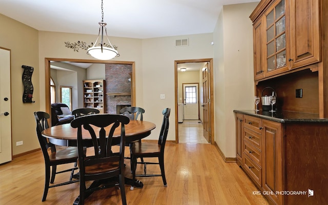 dining space featuring a brick fireplace and light wood-type flooring