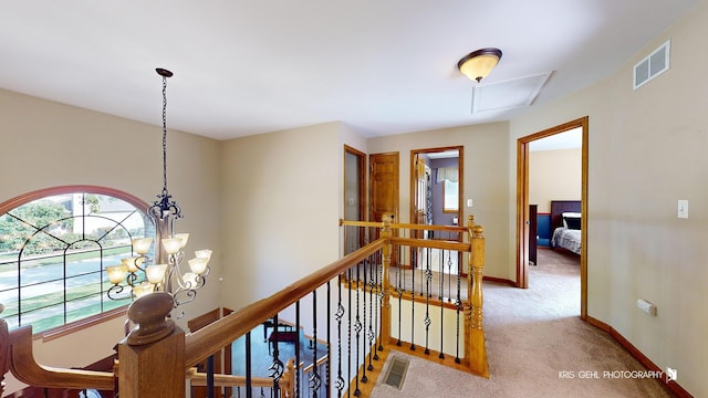 hallway featuring an inviting chandelier and carpet