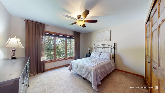 bedroom with light colored carpet, ceiling fan, and a closet