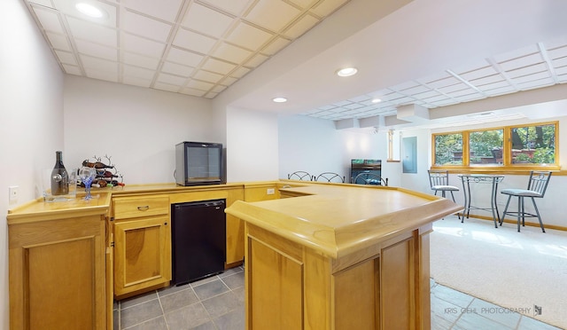 kitchen featuring a kitchen island, kitchen peninsula, fridge, and light carpet