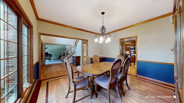 dining area featuring a chandelier, light hardwood / wood-style floors, and ornamental molding