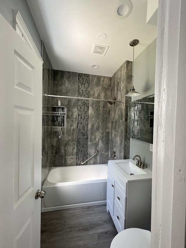 full bathroom with hardwood / wood-style floors, vanity, toilet, and tiled shower / bath