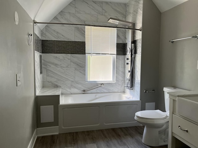 full bathroom featuring wood-type flooring, vaulted ceiling, toilet, vanity, and tiled shower / bath