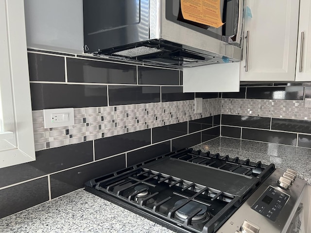 kitchen featuring white cabinetry, decorative backsplash, stone countertops, and appliances with stainless steel finishes