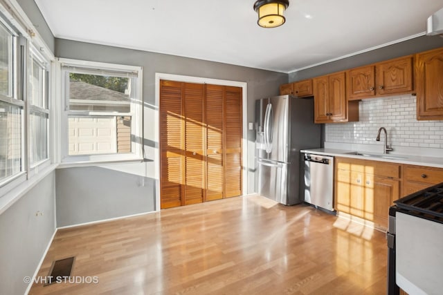 kitchen featuring decorative backsplash, sink, stainless steel appliances, and light hardwood / wood-style flooring