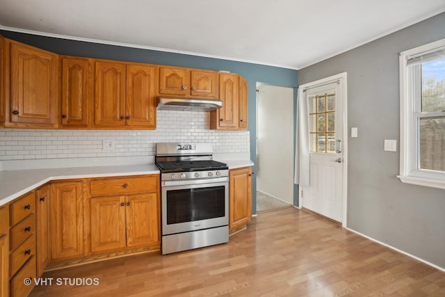 kitchen featuring decorative backsplash, light hardwood / wood-style flooring, exhaust hood, and stainless steel range oven