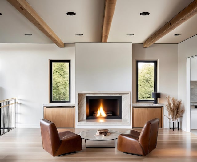 sitting room featuring a premium fireplace, light hardwood / wood-style flooring, and beamed ceiling