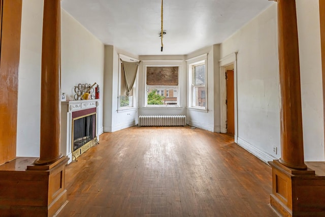 unfurnished living room with radiator heating unit, ornate columns, and hardwood / wood-style floors