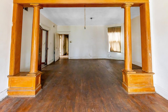 unfurnished living room featuring dark hardwood / wood-style floors and decorative columns