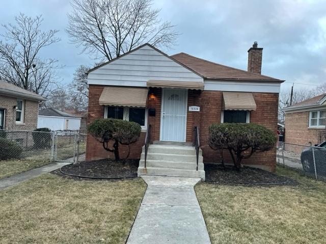 bungalow-style house with a chimney, fence, a front lawn, and brick siding