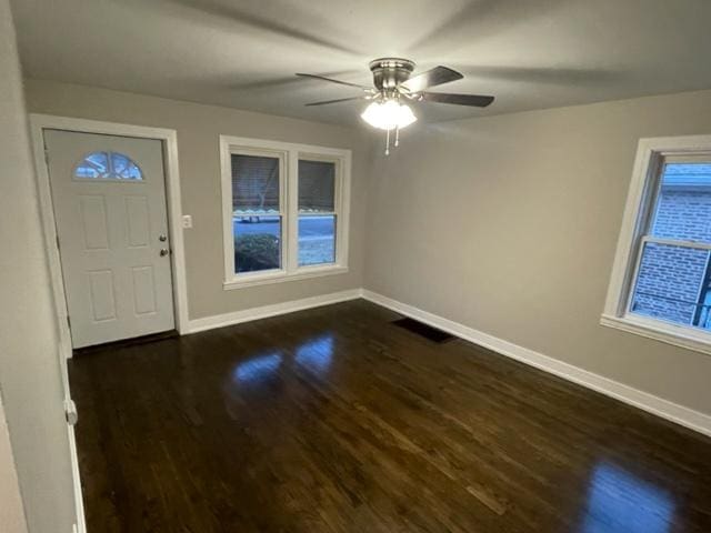 foyer with ceiling fan, visible vents, baseboards, and dark wood-type flooring