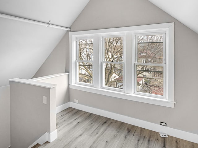 additional living space with light hardwood / wood-style floors and lofted ceiling