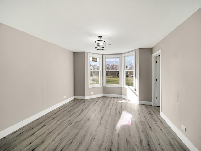 unfurnished room with light wood-type flooring and a notable chandelier