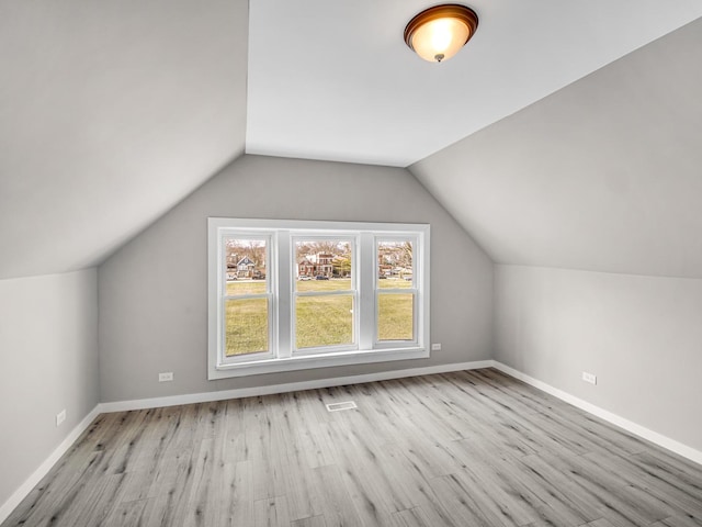 additional living space with light wood-type flooring and vaulted ceiling