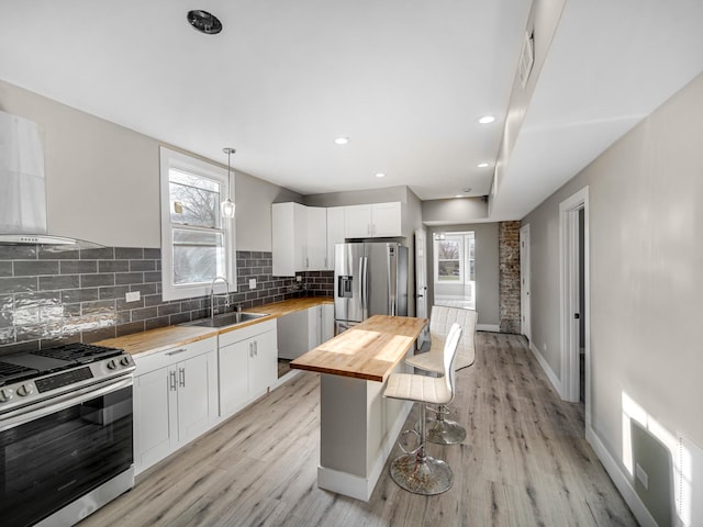 kitchen with wood counters, plenty of natural light, stainless steel appliances, and hanging light fixtures