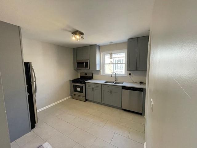 kitchen with pendant lighting, stainless steel appliances, light countertops, and gray cabinetry