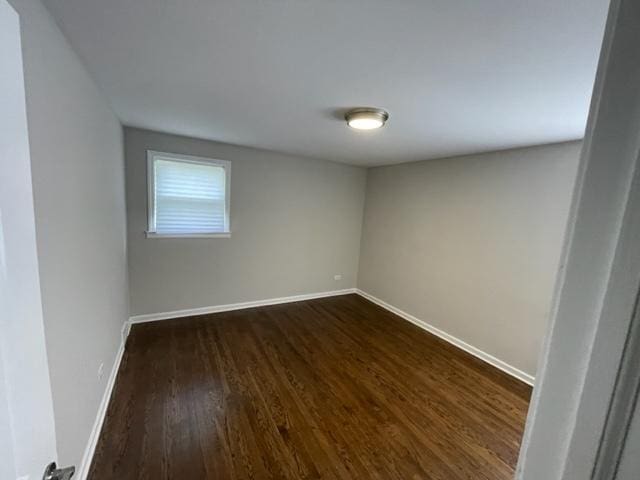 empty room featuring baseboards and dark wood finished floors