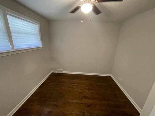 unfurnished room featuring a ceiling fan, visible vents, baseboards, and dark wood-type flooring