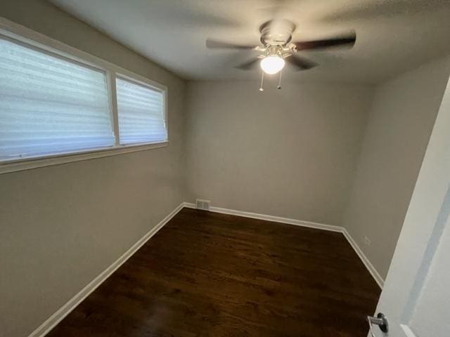 spare room with dark wood-style floors, baseboards, and a ceiling fan