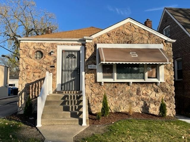 view of front of house featuring entry steps, stone siding, and a chimney