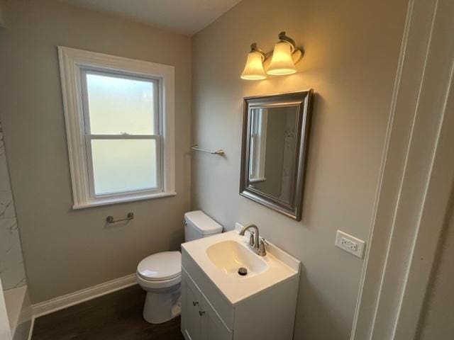 bathroom featuring toilet, vanity, baseboards, and wood finished floors